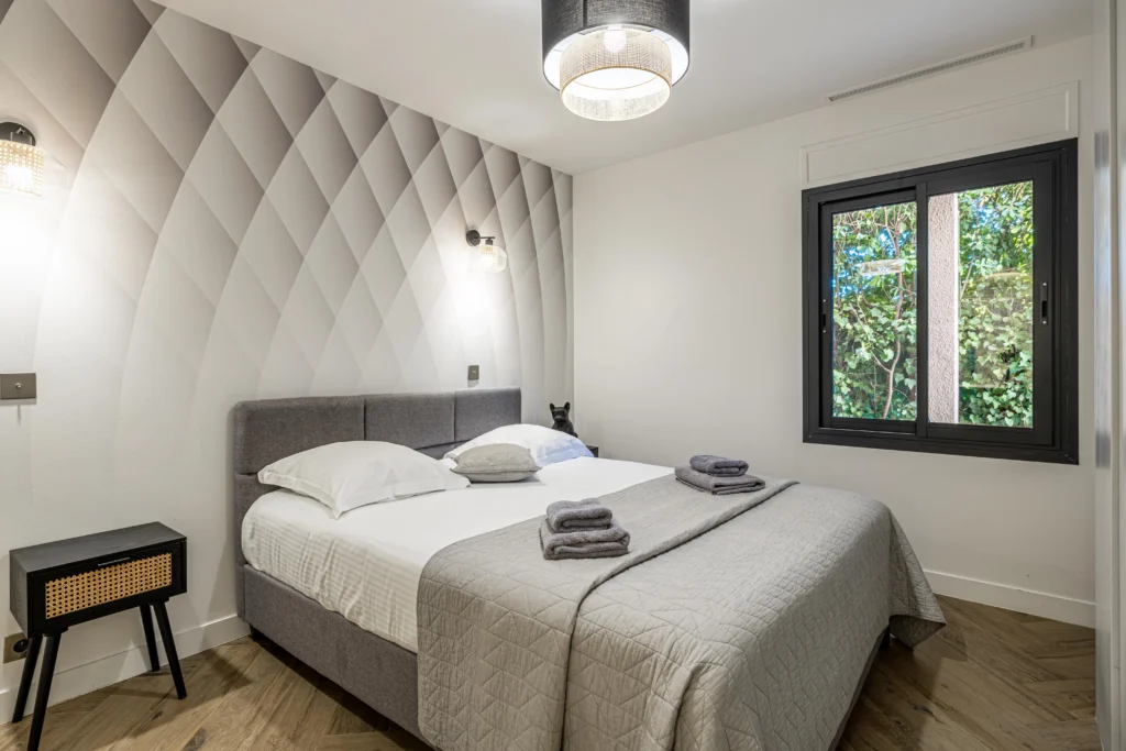Chambre moderne avec un lit deux personnes et une fenêtre avec vue sur un environnement verdoyant.